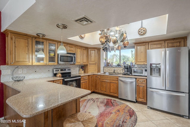 3910 S Via Del Ruisenor, Green Valley, AZ 85622 - kitchen featuring a kitchen bar, hanging light fixtures, light tile patterned floors, appliances with stainless steel finishes, and kitchen peninsula