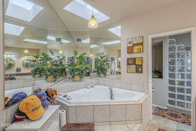 3910 S Via Del Ruisenor, Green Valley, AZ 85622 - bathroom featuring lofted ceiling with skylight, a relaxing tiled tub, and tile patterned floors