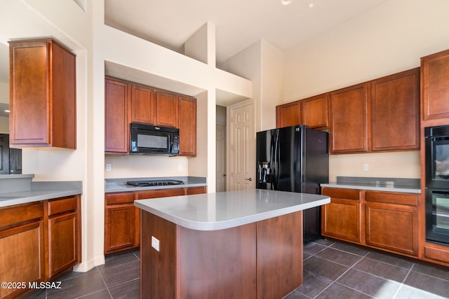 kitchen featuring a center island, dark tile patterned flooring, and black appliances