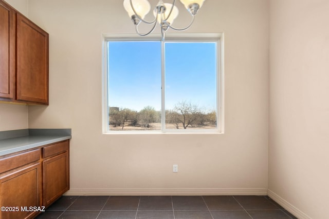 unfurnished dining area with dark tile patterned flooring and a chandelier