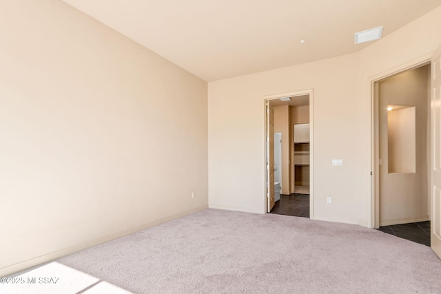 unfurnished bedroom featuring a walk in closet and dark colored carpet