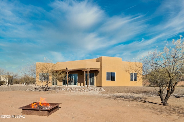 rear view of property featuring a fire pit