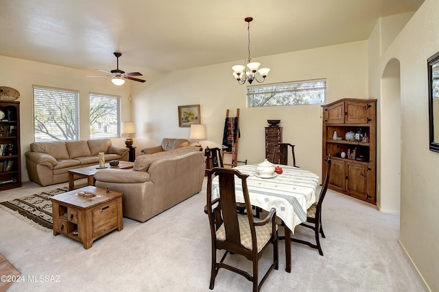 carpeted dining area with ceiling fan with notable chandelier