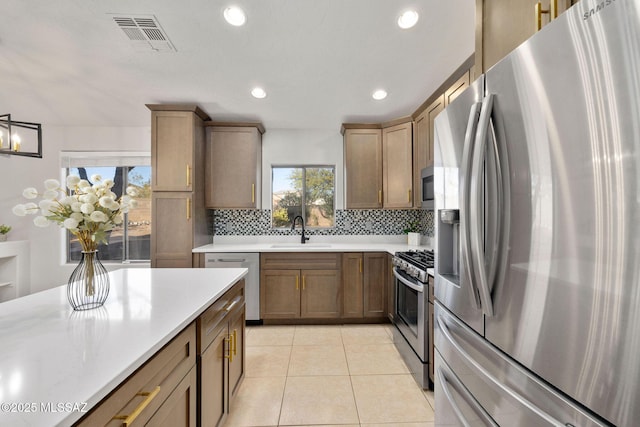 kitchen with light tile patterned floors, appliances with stainless steel finishes, sink, and backsplash