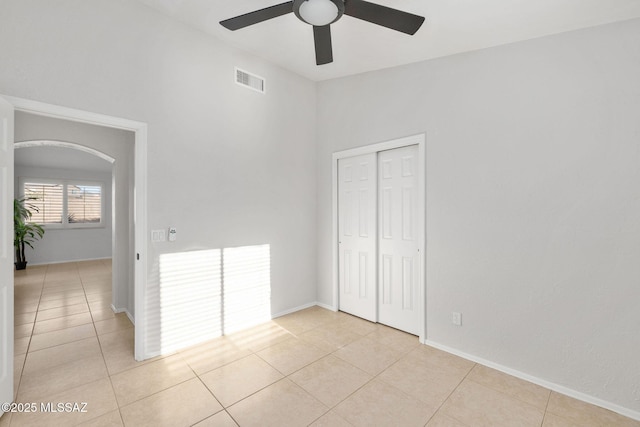 unfurnished bedroom with light tile patterned floors, ceiling fan, and a closet