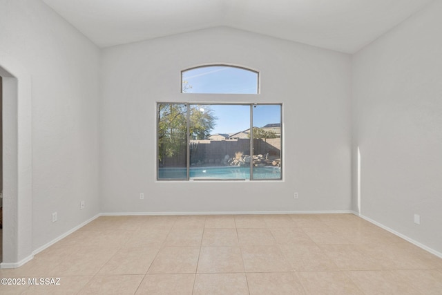 empty room with light tile patterned floors and vaulted ceiling