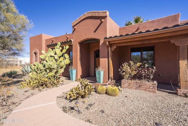 pueblo revival-style home with a tiled roof and stucco siding