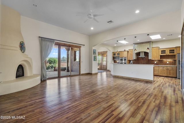 unfurnished living room with dark wood-type flooring, a large fireplace, and ceiling fan