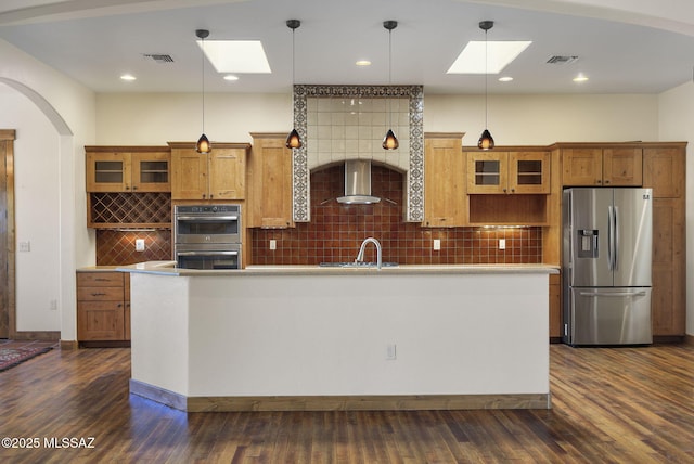 kitchen with stainless steel appliances, pendant lighting, dark hardwood / wood-style flooring, and wall chimney exhaust hood