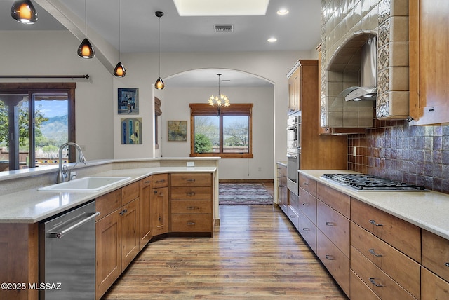 kitchen with sink, tasteful backsplash, decorative light fixtures, light wood-type flooring, and stainless steel appliances