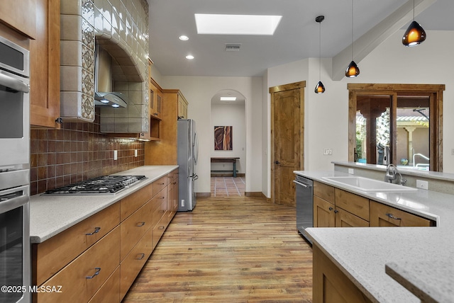 kitchen featuring pendant lighting, sink, light hardwood / wood-style flooring, backsplash, and stainless steel appliances