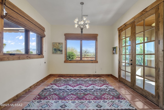 tiled empty room with an inviting chandelier and french doors