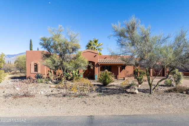 adobe home featuring a tile roof and stucco siding
