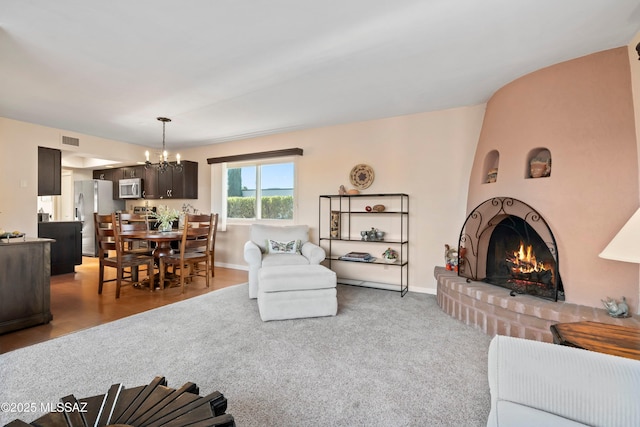 living room featuring an inviting chandelier and a brick fireplace