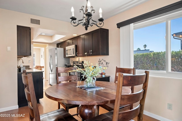 dining area featuring sink, an inviting chandelier, and light hardwood / wood-style flooring