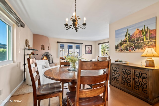 dining room featuring light wood-type flooring, an inviting chandelier, and a fireplace