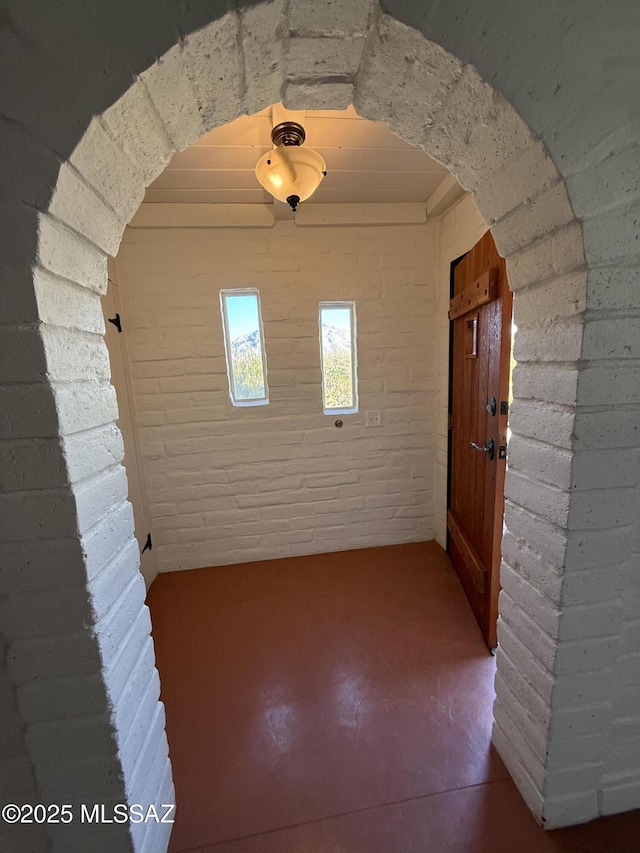 spare room featuring concrete floors and brick wall