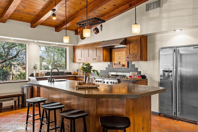 kitchen with hanging light fixtures, sink, high end refrigerator, and wall chimney exhaust hood