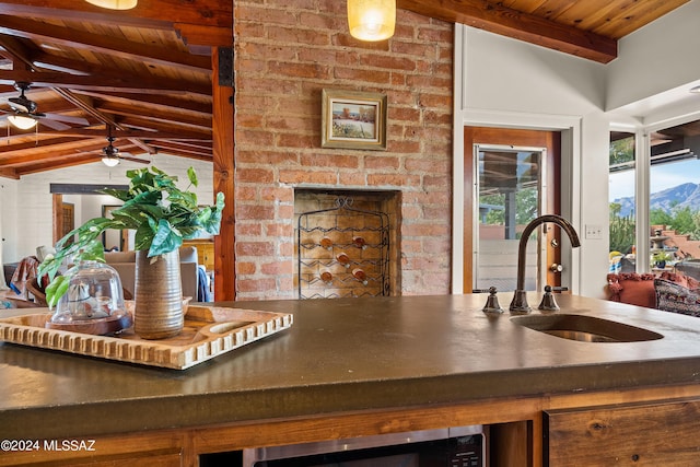 kitchen featuring sink, vaulted ceiling with beams, wood ceiling, a mountain view, and a fireplace