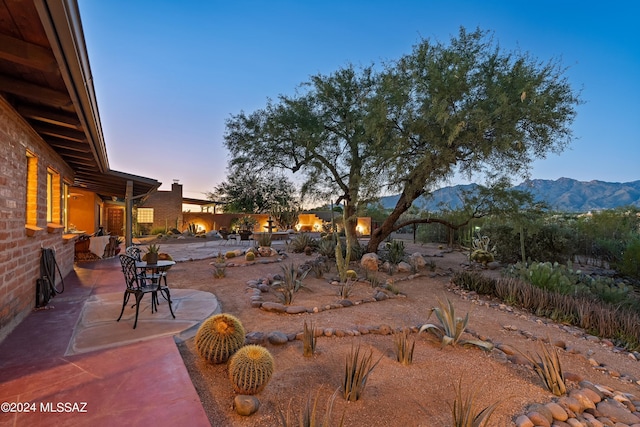 yard at dusk featuring a mountain view and a patio