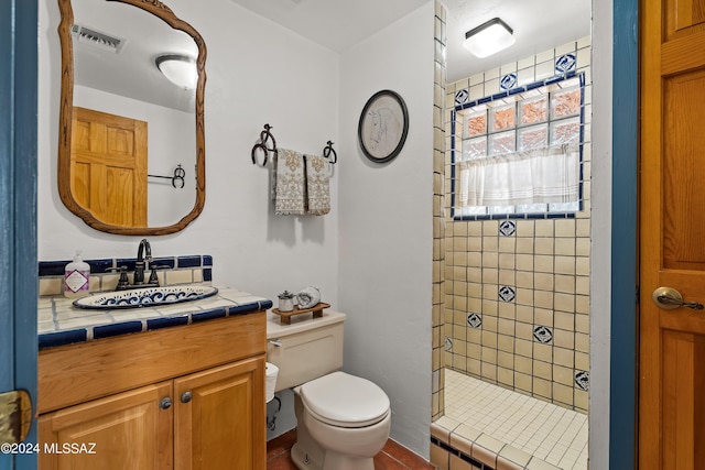 bathroom featuring vanity, toilet, and tiled shower