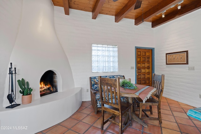 dining room featuring beam ceiling, tile patterned flooring, wooden ceiling, and a fireplace