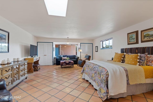 tiled bedroom featuring a skylight and two closets