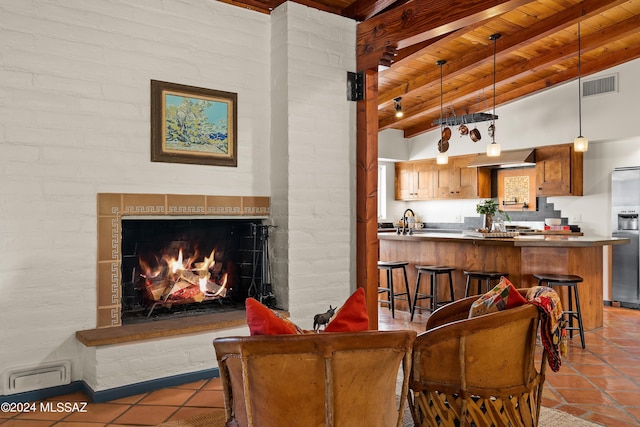 living room with lofted ceiling with beams, sink, light tile patterned floors, and wooden ceiling