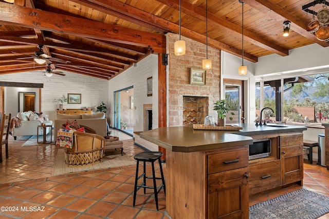 kitchen featuring pendant lighting, an island with sink, sink, a breakfast bar area, and wooden ceiling