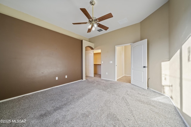 unfurnished bedroom featuring a walk in closet, light colored carpet, ceiling fan, and vaulted ceiling