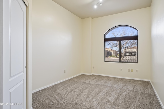 carpeted empty room with rail lighting