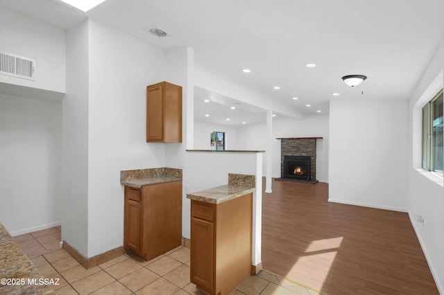 kitchen with a stone fireplace and light hardwood / wood-style floors