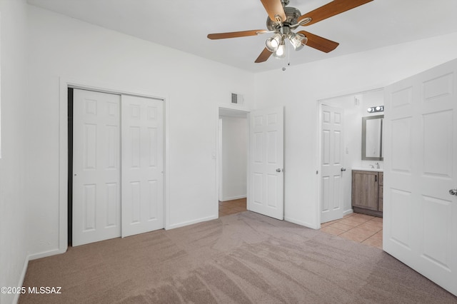 unfurnished bedroom featuring lofted ceiling, ceiling fan, connected bathroom, light carpet, and a closet