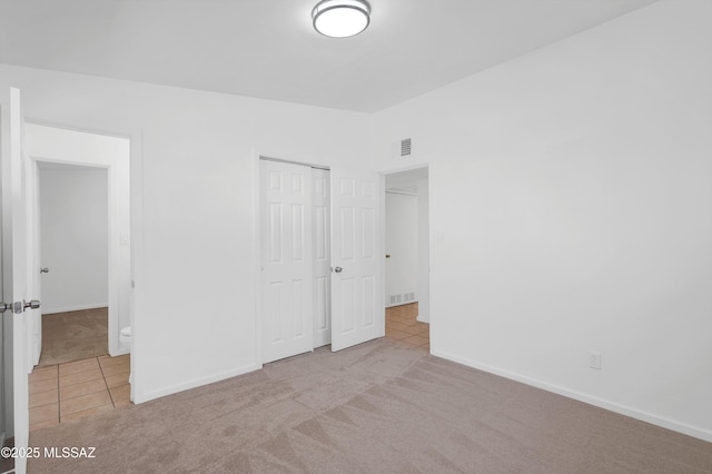 unfurnished bedroom with light colored carpet, vaulted ceiling, and a closet