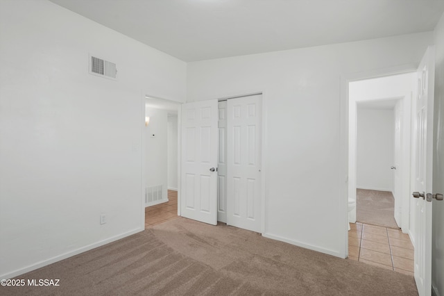 unfurnished bedroom with light carpet and a closet