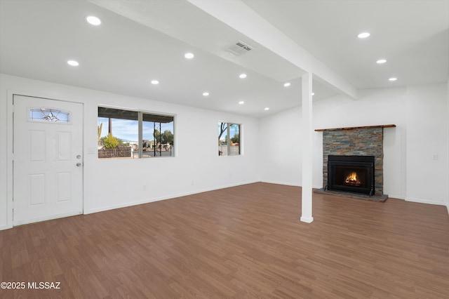 unfurnished living room with dark hardwood / wood-style floors, a stone fireplace, and lofted ceiling with beams