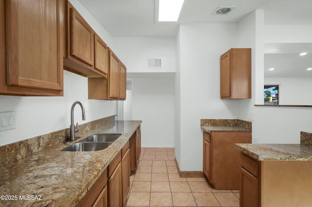 kitchen featuring light tile patterned floors, sink, and stone counters