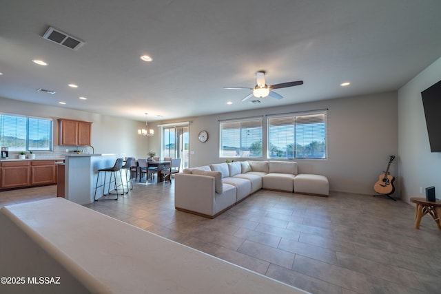 living room featuring light tile patterned flooring, ceiling fan with notable chandelier, and a wealth of natural light