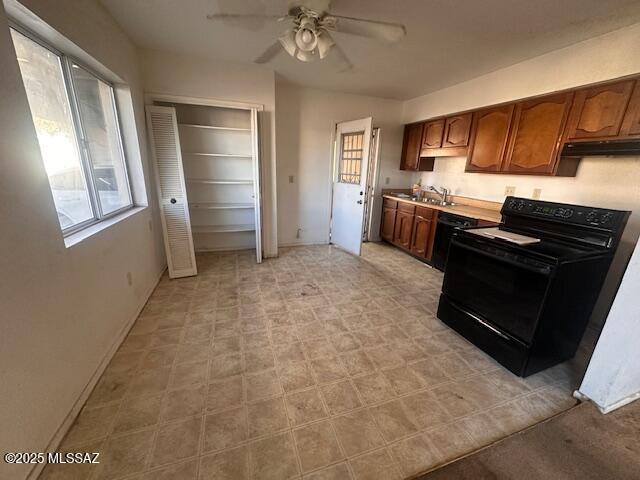 kitchen featuring baseboards, a ceiling fan, under cabinet range hood, black range with electric cooktop, and a sink