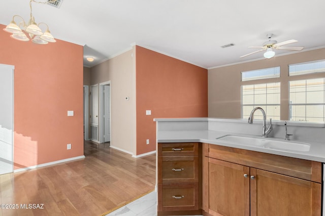 kitchen with sink, hanging light fixtures, ceiling fan, light hardwood / wood-style floors, and crown molding