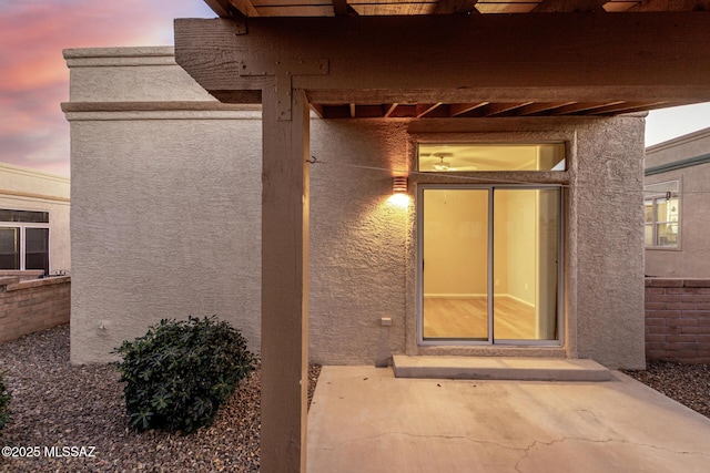 exterior entry at dusk featuring a patio area