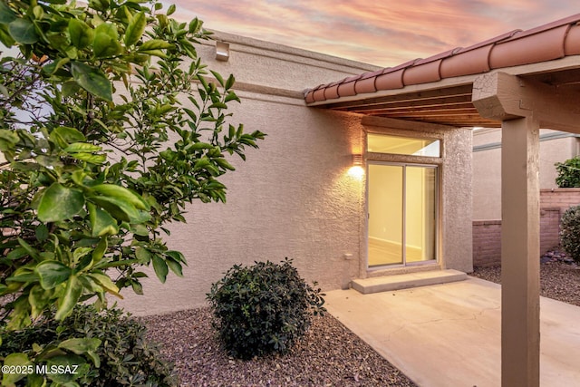 exterior entry at dusk featuring a patio area