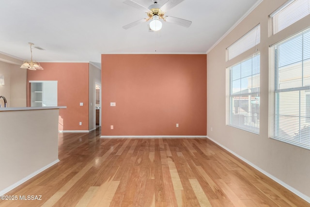 unfurnished living room featuring ceiling fan with notable chandelier, ornamental molding, sink, and light hardwood / wood-style floors