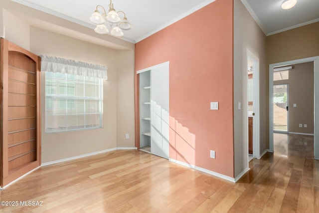 spare room featuring hardwood / wood-style flooring, crown molding, and a chandelier