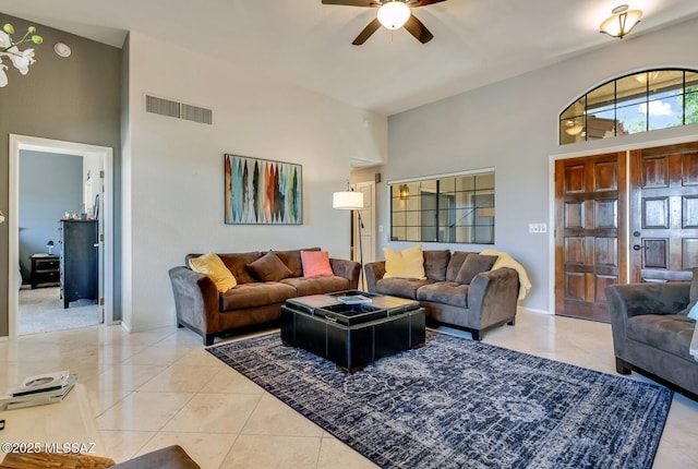 living room with a towering ceiling, light tile patterned floors, and ceiling fan