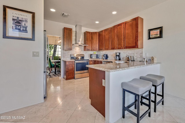 kitchen with wall chimney range hood, backsplash, sink, and appliances with stainless steel finishes