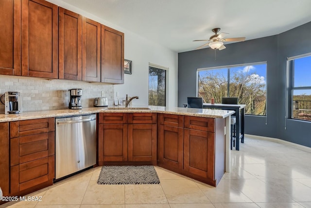 kitchen featuring sink, backsplash, stainless steel dishwasher, and a healthy amount of sunlight
