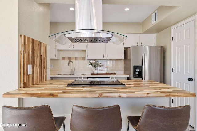 kitchen with island range hood, sink, a breakfast bar area, white cabinets, and stainless steel refrigerator with ice dispenser