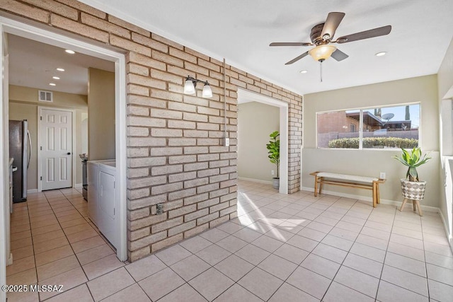 interior space with ceiling fan, washing machine and clothes dryer, and brick wall