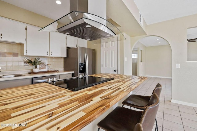 kitchen with sink, stainless steel appliances, island exhaust hood, white cabinets, and light tile patterned flooring